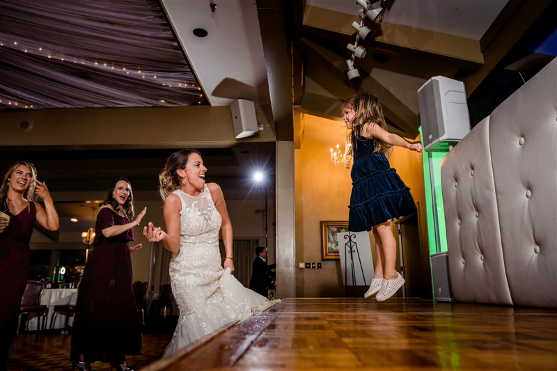 frontwedding03 - Stylus Weddings Bride dancing with a young guest during the wedding reception.