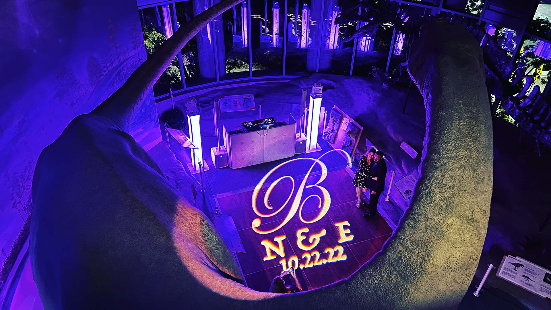 Wedding DJ setup with purple uplighting and a custom monogram projection.